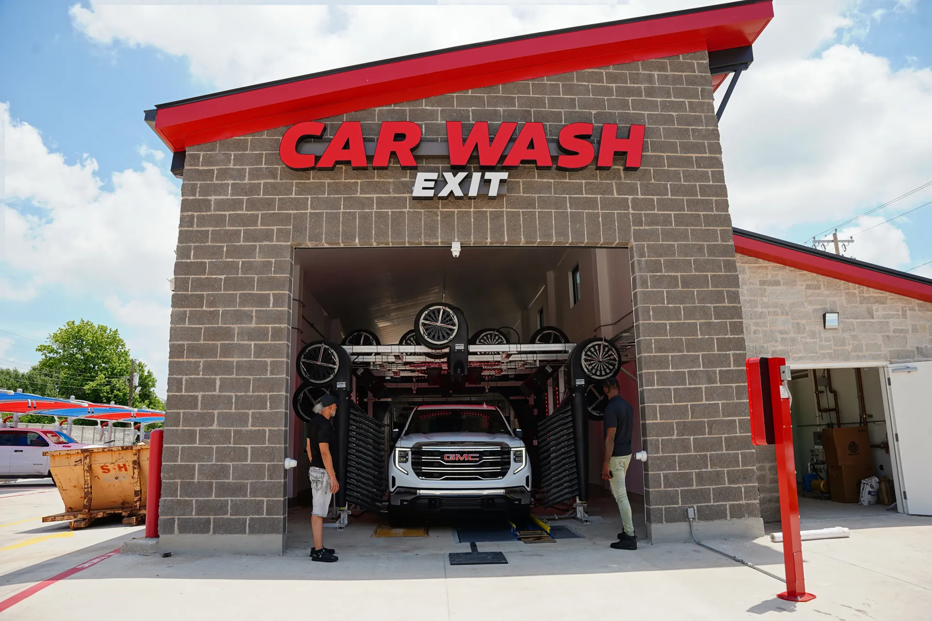 White truck exiting the car wash with 2 happy employees on either side